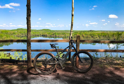 Bicycle by lake against sky