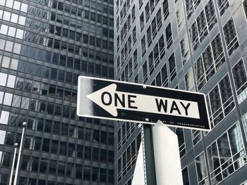 Low angle view of road sign against buildings in city