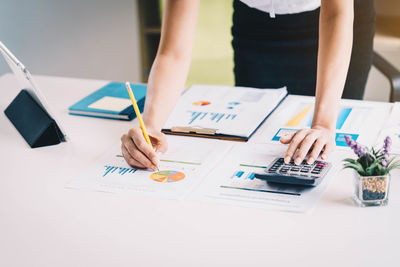 Midsection of businesswoman working at desk in office