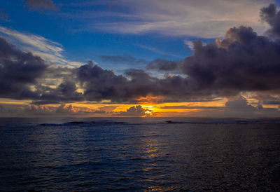 Scenic view of sea against dramatic sky during sunrise