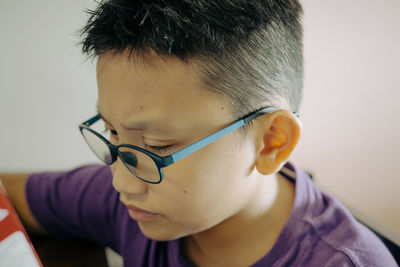 Portrait of young boy wearing glasses looking down at home. low angle view.