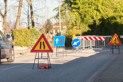 Road signs on street against trees