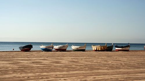 Boats in calm sea against clear sky