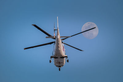 Helicopter in flight against clear sky and full moon