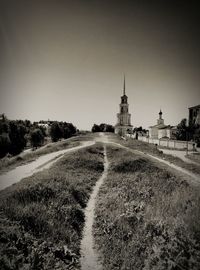 Road amidst field against clear sky