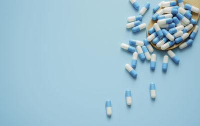 Capsules spilling from bottle against blue background