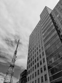 Low angle view of crane by building against sky