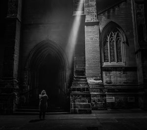 Rear view of man standing outside temple against building