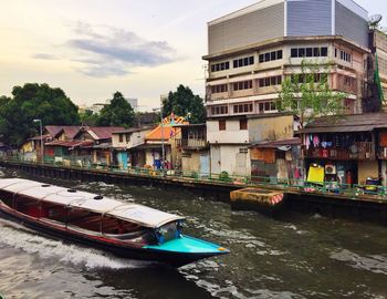 Boats moored in canal by buildings in city against sky