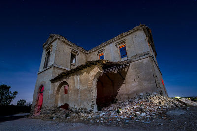 Low angle view of abandoned building against sky at night