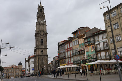 People walking on street amidst buildings in town against sky