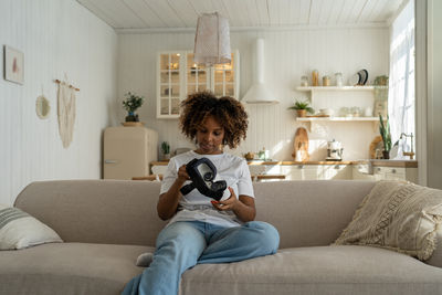 Young woman using mobile phone while sitting at home