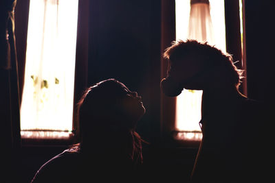 Side view of girl looking at stuffed toy at home