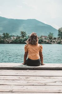 Rear view of woman looking at lake against sky