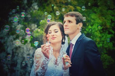 Smiling young couple amidst bubbles at park