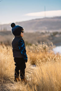 Boy standing on field against sky