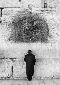 Rear view of a man standing against wall