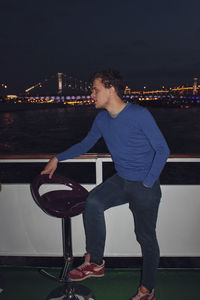 Man sitting in illuminated city at night