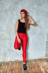 Full length of young woman standing against wall