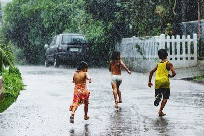 Full length of children on wet road during rainy season