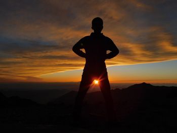 Silhouette man standing on mountain against sunset sky