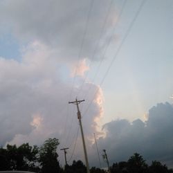 Low angle view of power lines against cloudy sky