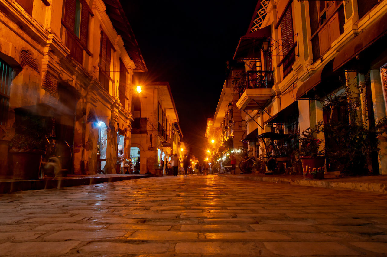 ILLUMINATED STREET AMIDST BUILDINGS IN TOWN