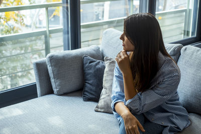 Young woman using laptop while sitting on sofa at home