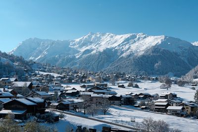 Snow covered houses and buildings in city against sky