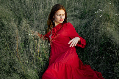 Portrait of young woman standing against plants