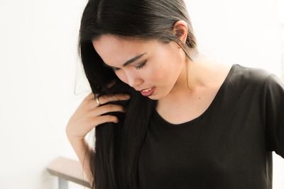 Close-up of young woman standing against white background