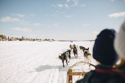 People on snow covered land against sky