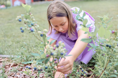 Portrait of cute girl picking flowers on field