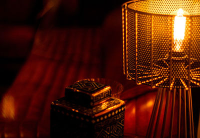 Close-up of illuminated lamp by container on table in darkroom