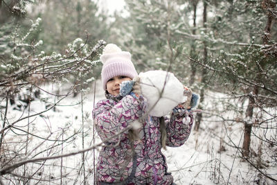 Portrait of smiling girl holding snowball during winter