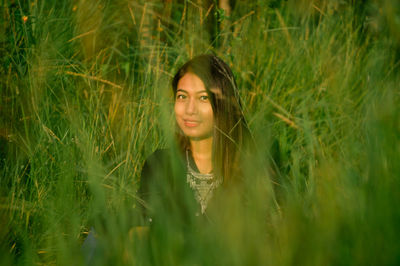 Portrait of young woman amidst grass