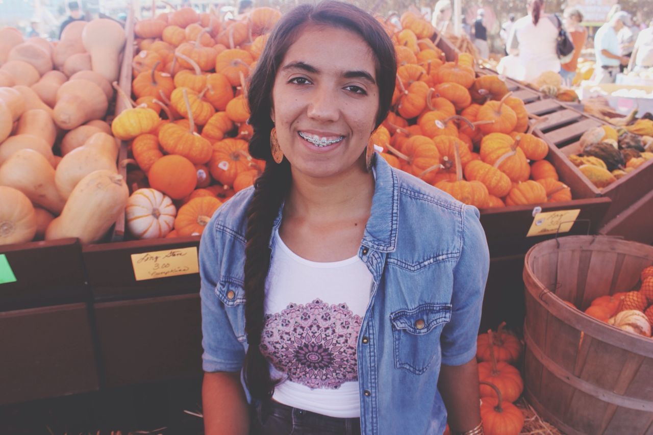 lifestyles, retail, food and drink, for sale, casual clothing, market stall, market, standing, person, leisure activity, food, freshness, front view, looking at camera, portrait, smiling, holding, abundance