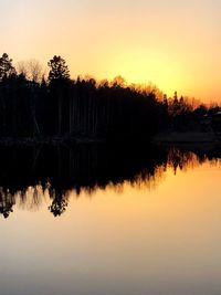 Silhouette trees by lake against sky during sunset