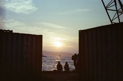 Silhouette people on beach against sky during sunset