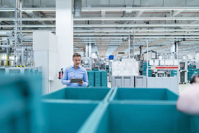 Businessman with tablet in a factory hall