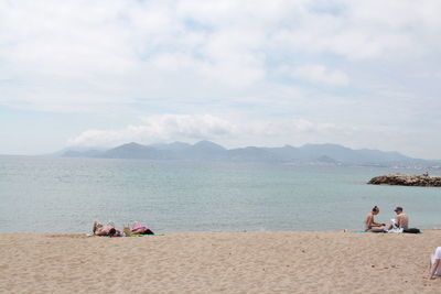 People at beach against sky