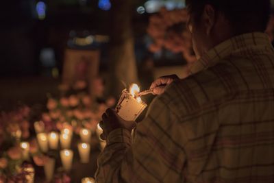 Man burning candles at night