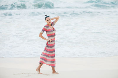 Full length portrait of young woman standing at beach