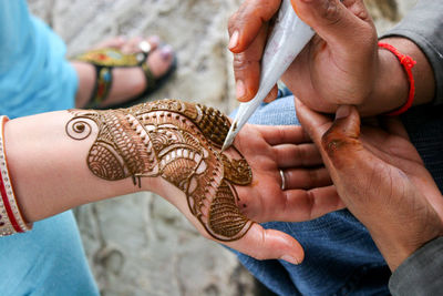 Cropped image of man making henna tattoo on woman hand