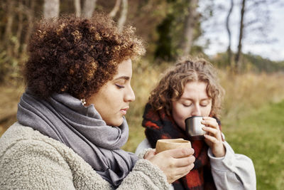 Female friends drinking hot drinks in nature