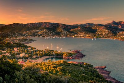 High angle view of cityscape by sea against sky during sunset