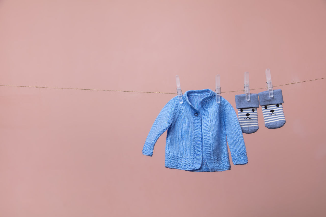 CLOSE-UP OF CLOTHES HANGING ON CLOTHESLINE AGAINST WALL