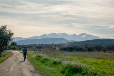 Rear view of man walking on footpath against mountains