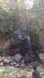 People sitting on rock at riverbank