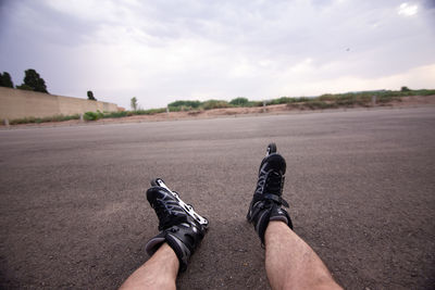 Low section of man sitting with roller skates on land